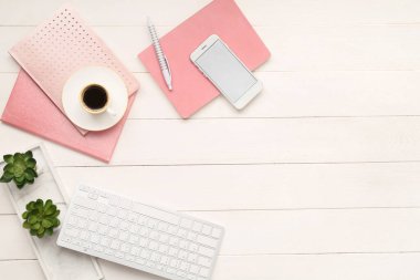 Cep telefonu, bilgisayar klavyesi, bir fincan kahve ve ahşap arka planda kırtasiye.