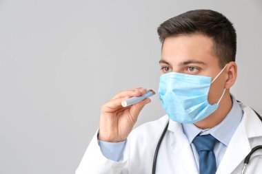 Gri arka planda el feneri olan erkek doktor.