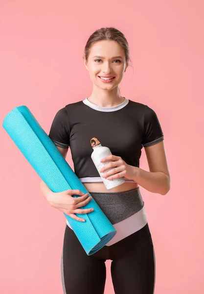 有瑜伽垫和彩色背景瓶装水的胖胖的年轻女子 — 图库照片