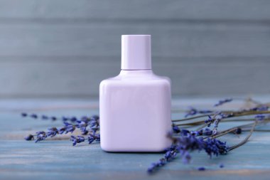 Ahşap arkaplanda lavanta çiçekleri olan bir şişe parfüm.