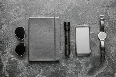 Cep telefonu, defter, güneş gözlüğü ve koyu arkaplanda saati olan modern el feneri.