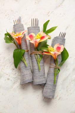 Çiçekli peçeteler ve arka planda çatal bıçak takımı.
