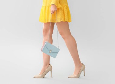 Gri arka planda şık çantalı güzel bir kadın.