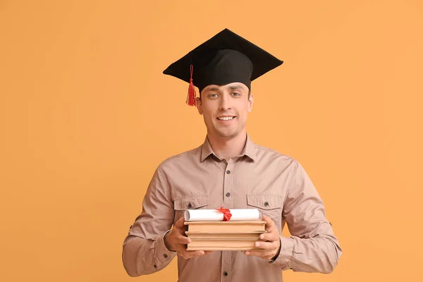 卒業帽子の若い男 卒業証書と色の背景の本 — ストック写真
