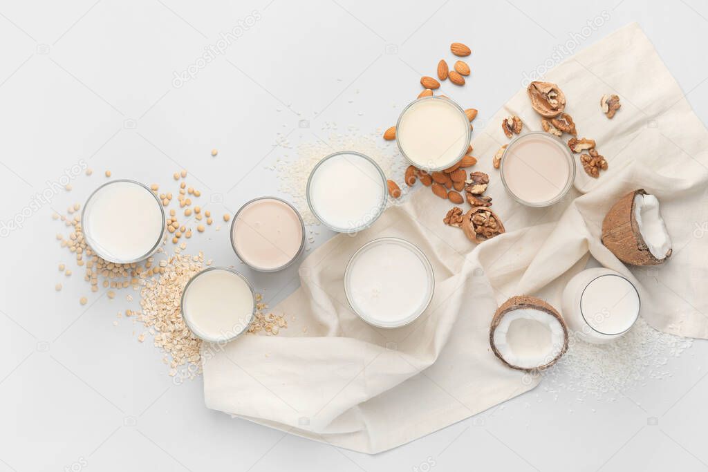 Glasses of different milk on white background