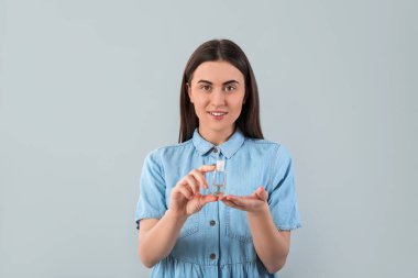 Gri arkaplanda dezenfektan olan kadın.