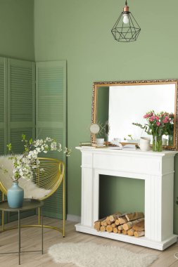 Şömineli, şık aynalı ve çiçekli bir oturma odası.