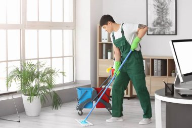 Erkek hademe ofiste yerleri paspaslıyor.