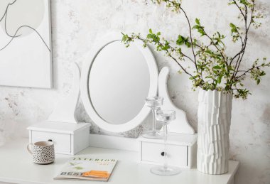 Tarz aynası ve çiçek açan ağaç dalları olan masa.