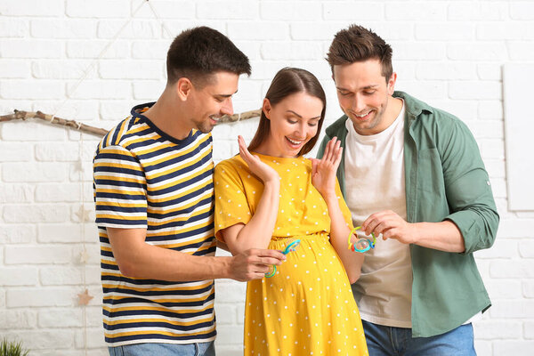 Гей пара и беременная женщина с игрушками дома
