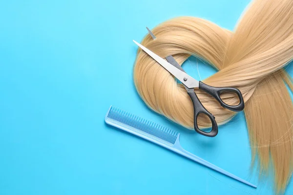 长长的金发 剪子和梳子的彩色背景 — 图库照片
