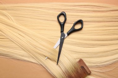 Renkli arkaplanda uzun sarı saç, tarak ve makas