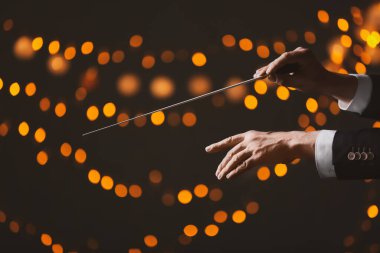 Koyu arkaplandaki erkek kondüktörün elleri ve sönmüş ışıklar