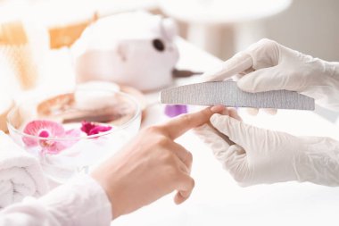 Manikür ustası kadın müşteriyle güzellik salonunda çalışıyor.