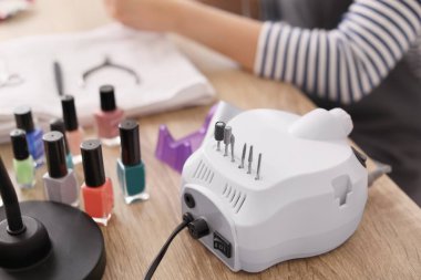 Manikür ustası güzellik salonunda modern değirmenciyle çalışıyor.