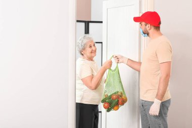Kıdemli kadın evde kuryeden yemek alıyor. Salgın kavramı