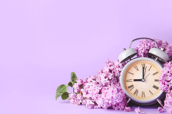 Будильник и цветы на цветном фоне. Весеннее время
