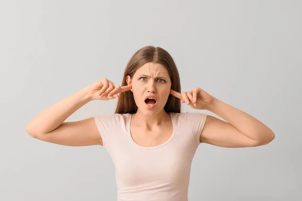 Young Woman Suffering Loud Noise Light Background — Stock Photo, Image