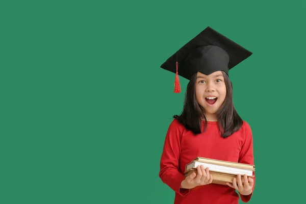 小さな女の子で卒業帽子と本の色の背景 — ストック写真