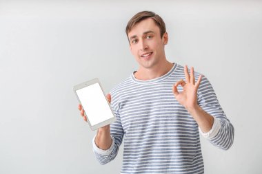 Tablet bilgisayarlı genç adam arka planda iyi görünüyor.