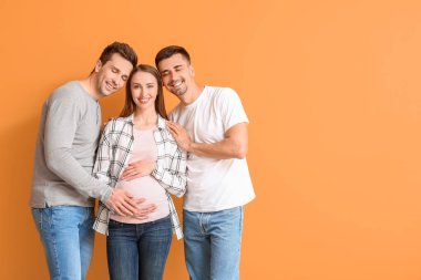Renkli arka planda hamile bir kadınla eşcinsel çift
