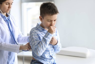 Öksüren küçük çocuk klinikteki doktoru ziyaret ediyor.