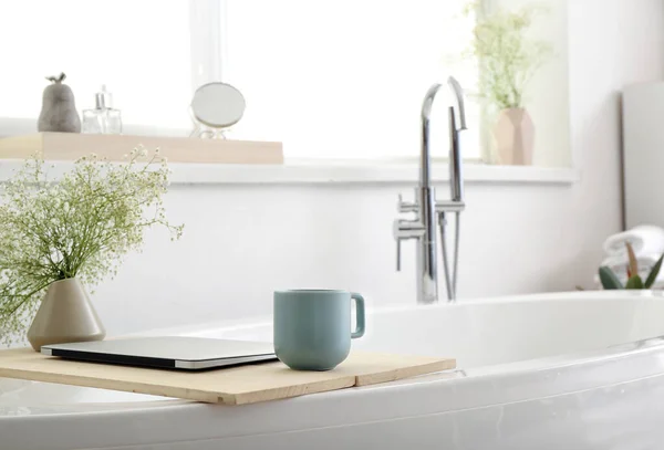 Ständer Mit Floralem Dekor Laptop Und Tasse Kaffee Auf Badewanne — Stockfoto