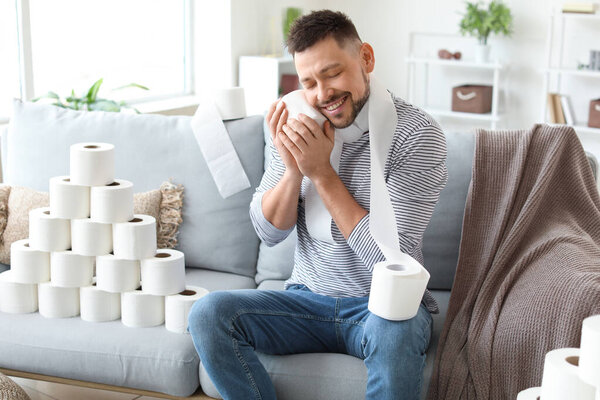 Happy man with toilet paper at home. Concept of coronavirus epidemic