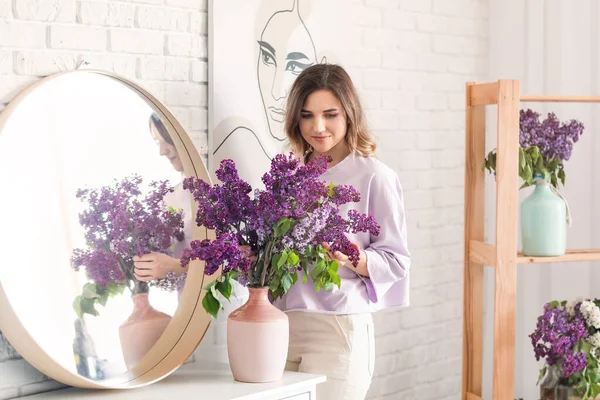自宅でライラックの花の花束を持つ美しい若い女性 — ストック写真