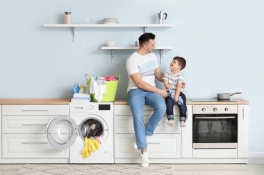 Adam ve küçük oğlu evde çamaşır yıkıyorlar.