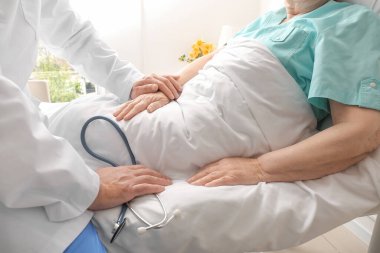 Hasta odasında yaşlı bir hastayla çalışan erkek doktor.
