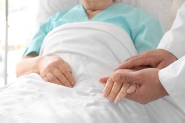 Hasta odasında yaşlı bir hastayla erkek doktor.