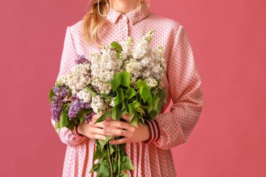 Beautiful young woman with lilac flowers on color background