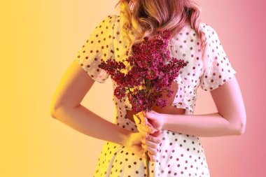 Beautiful young woman with lilac flowers on color background