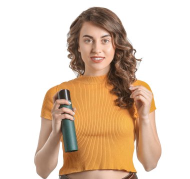 Beyaz arka planda saç spreyi olan güzel bir genç kadın.