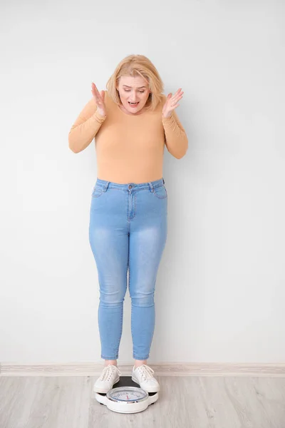 白い壁の近くのスケールで太りすぎの女性に悩みました 減量の概念 — ストック写真