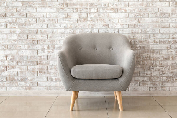 Comfortable armchair near brick wall
