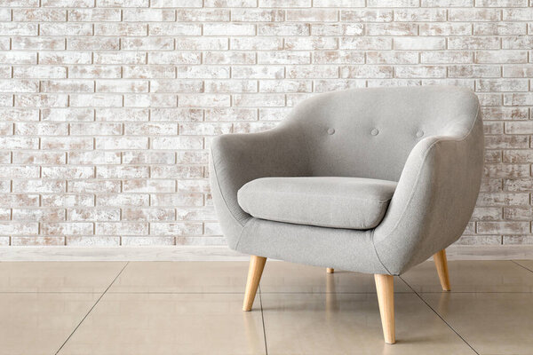 Comfortable armchair near brick wall