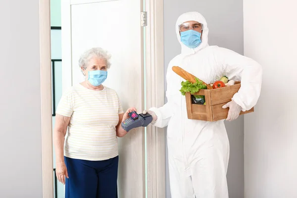 老年妇女通过终端向食品递送公司的快递员支付定货费用 流行病的概念 — 图库照片