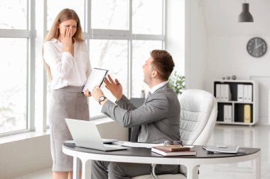 Kızgın patron ofisinde sekreterini azarlıyor.