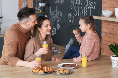 Mutlu bir aile mutfakta kahvaltı yapıyor.