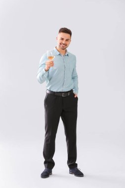 Gri arka planda bir bardak şampanyası olan mutlu adam.