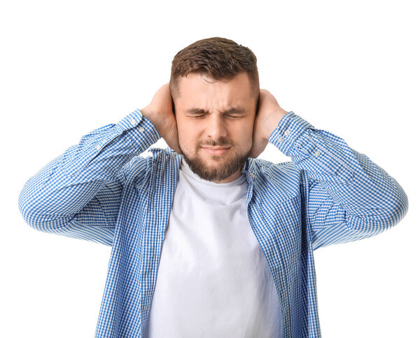 Young man suffering from loud noise on white background