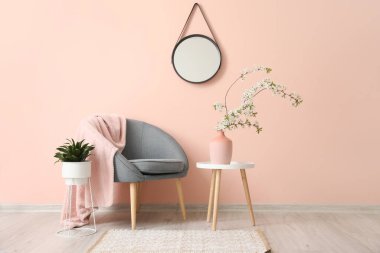 Şık aynalı ve çiçek açan ağaç dalları olan oturma odasının içinde.