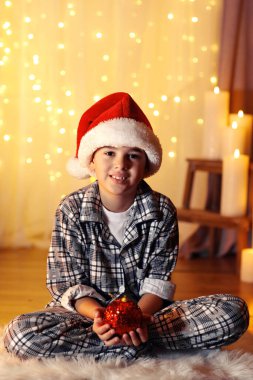 Küçük çocuk şöminenin yanında oturuyor.