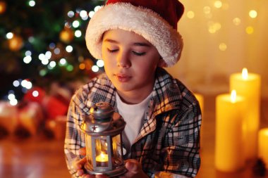 Küçük çocuk şöminenin yanında oturuyor.