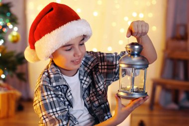 Küçük çocuk şöminenin yanında oturuyor.