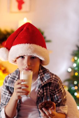 Küçük çocuk şöminenin yanında oturuyor.