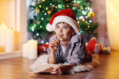 Küçük çocuk şöminenin yanında oturuyor.