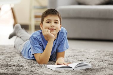 Kitaplı çocuk evde yerde yatıyor.